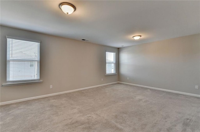 unfurnished room featuring light colored carpet and plenty of natural light