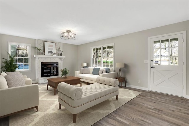 living room featuring a chandelier, a fireplace, wood finished floors, and baseboards