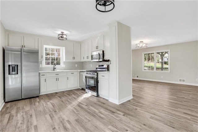 kitchen with light wood finished floors, light countertops, appliances with stainless steel finishes, and decorative backsplash