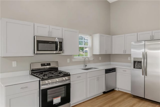1011 Riverclift Dr, Covington, GA 30016 - kitchen featuring stainless steel appliances, a sink, light countertops, a towering ceiling, and white cabinets