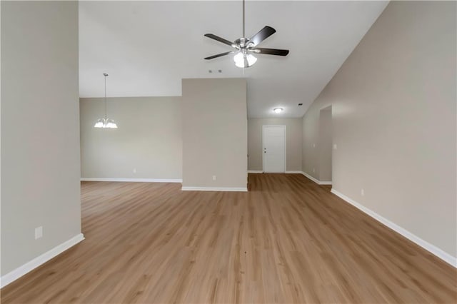 1011 Riverclift Dr, Covington, GA 30016 - unfurnished room featuring a ceiling fan, light wood finished floors, baseboards, vaulted ceiling, and a chandelier