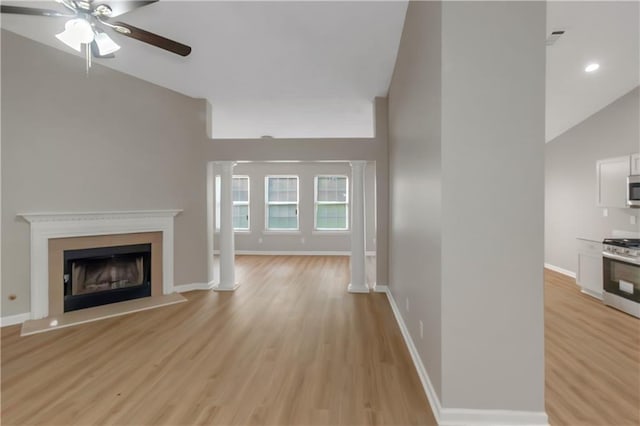 1011 Riverclift Dr, Covington, GA 30016 - unfurnished living room featuring ceiling fan, decorative columns, vaulted ceiling, light wood finished floors, and a fireplace