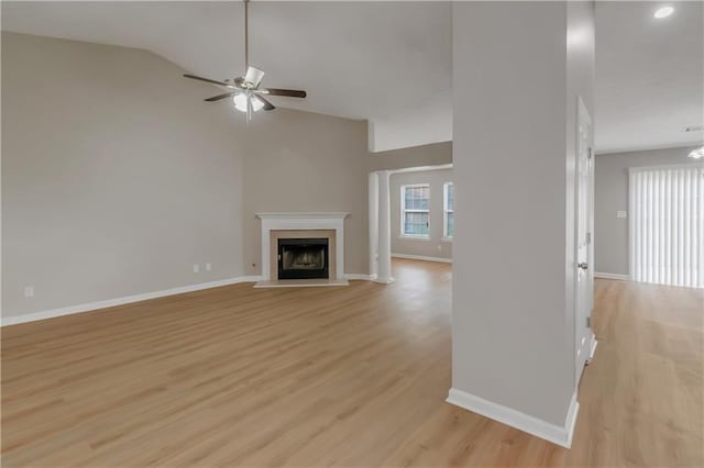 1011 Riverclift Dr, Covington, GA 30016 - unfurnished living room with ceiling fan, light wood-style floors, a fireplace with raised hearth, baseboards, and high vaulted ceiling