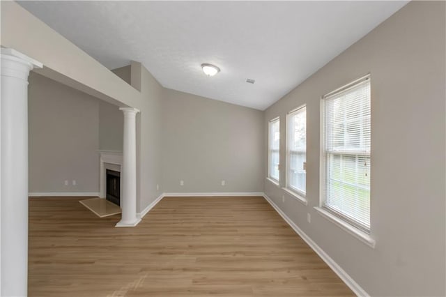 1011 Riverclift Dr, Covington, GA 30016 - unfurnished living room featuring light wood-style flooring, ornate columns, baseboards, and a fireplace with raised hearth