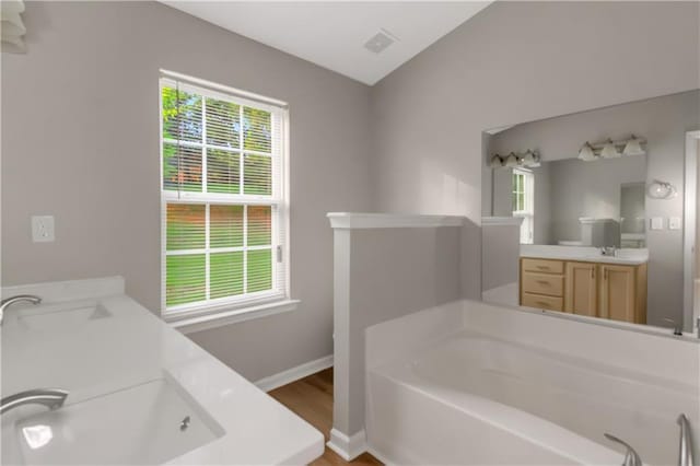 1011 Riverclift Dr, Covington, GA 30016 - bathroom with a bath, double vanity, baseboards, and wood finished floors