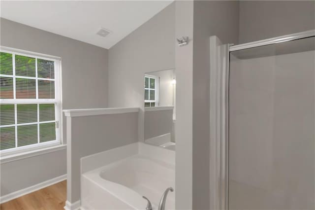 1011 Riverclift Dr, Covington, GA 30016 - full bathroom with vaulted ceiling, a shower stall, a garden tub, wood finished floors, and baseboards