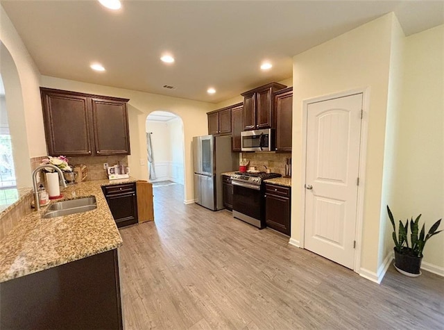 57 Matador, Newnan, GA 30263 - kitchen featuring arched walkways, stainless steel appliances, a sink, dark brown cabinets, and decorative backsplash