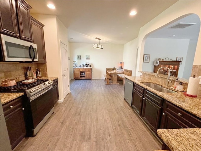 57 Matador, Newnan, GA 30263 - kitchen with appliances with stainless steel finishes, a sink, arched walkways, light wood-style floors, and backsplash