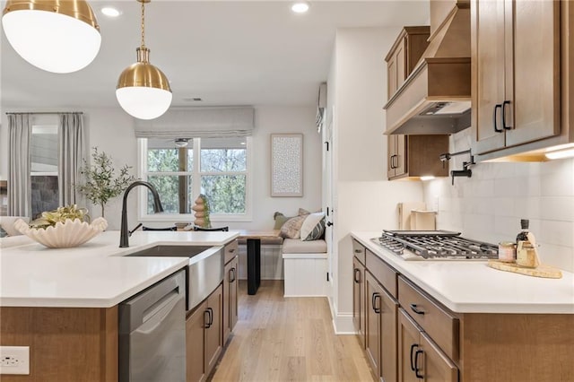 kitchen featuring premium range hood, sink, backsplash, hanging light fixtures, and stainless steel appliances