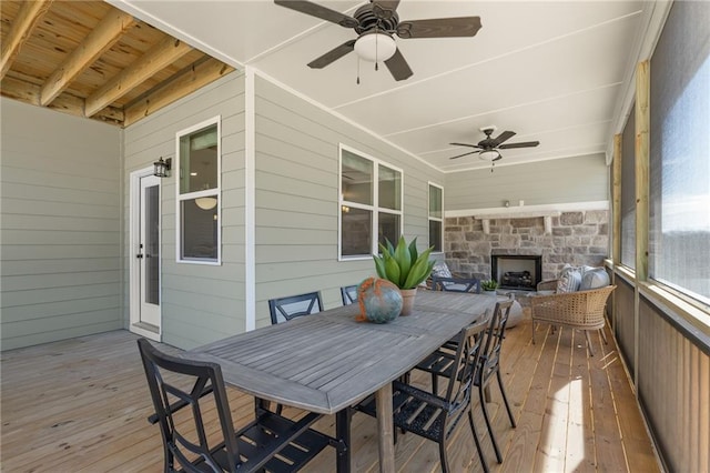 wooden deck with ceiling fan and an outdoor stone fireplace