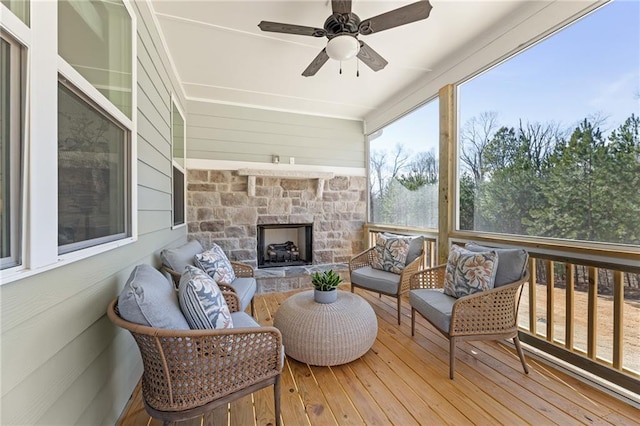 sunroom / solarium featuring a stone fireplace and ceiling fan