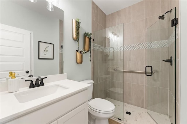 bathroom featuring vanity, a shower with shower door, and toilet