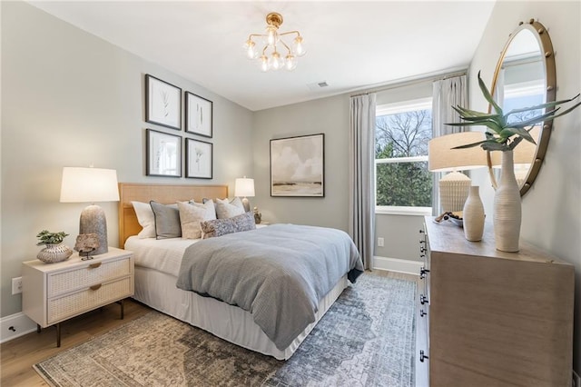 bedroom with hardwood / wood-style flooring and an inviting chandelier