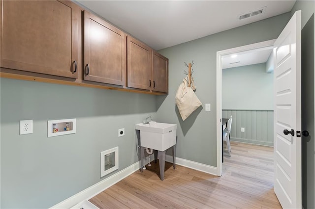 laundry area with hookup for a washing machine, light hardwood / wood-style floors, cabinets, and hookup for an electric dryer