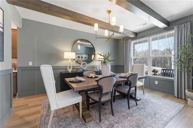 dining room with beamed ceiling, a chandelier, and light wood-type flooring