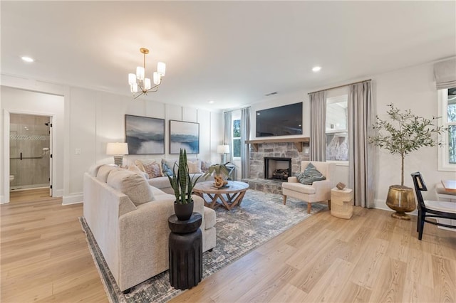 living room with a healthy amount of sunlight, a notable chandelier, a fireplace, and light hardwood / wood-style flooring