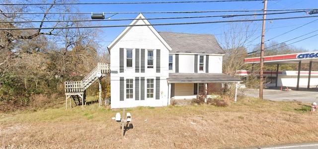 view of front facade with a shingled roof and stairs