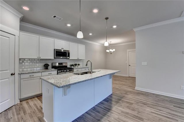 kitchen featuring light wood-style flooring, stainless steel appliances, a sink, visible vents, and backsplash