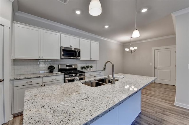 kitchen with a sink, appliances with stainless steel finishes, tasteful backsplash, a center island with sink, and crown molding