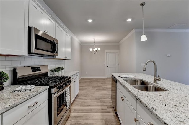 kitchen with stainless steel appliances, a sink, white cabinets, ornamental molding, and backsplash