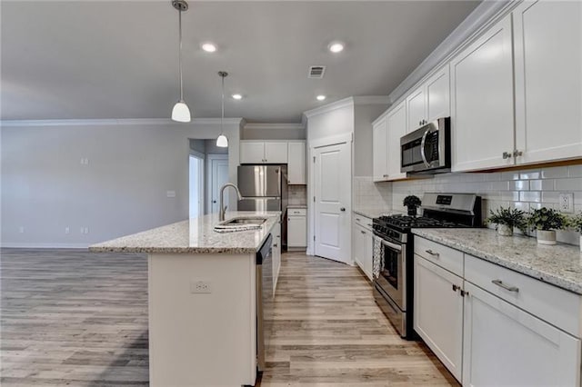 kitchen featuring stainless steel appliances, a sink, light wood-style floors, tasteful backsplash, and crown molding