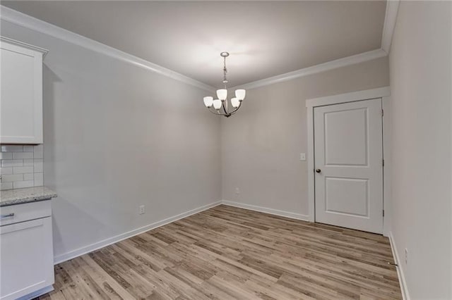 unfurnished dining area with baseboards, crown molding, light wood finished floors, and an inviting chandelier