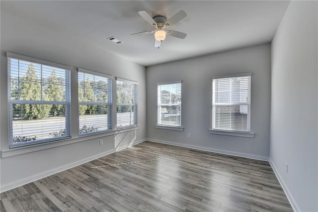 unfurnished room featuring a ceiling fan, wood finished floors, visible vents, and baseboards