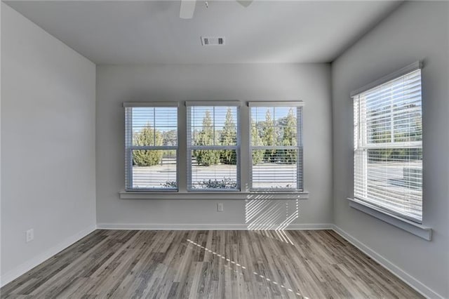 spare room with visible vents, ceiling fan, baseboards, and wood finished floors