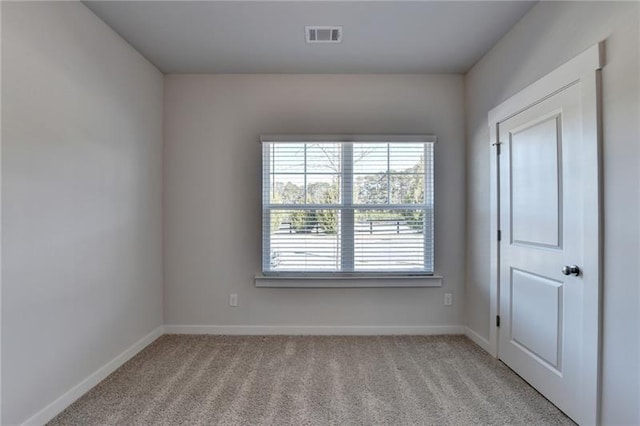 empty room featuring baseboards, visible vents, and light colored carpet