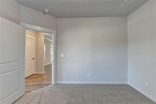 unfurnished room featuring carpet floors, visible vents, and baseboards