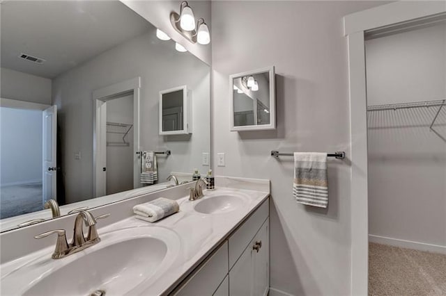 bathroom with double vanity, baseboards, visible vents, and a sink