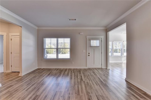 entryway with ornamental molding, wood finished floors, visible vents, and baseboards