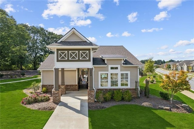 view of front facade with a front lawn, a shingled roof, and brick siding