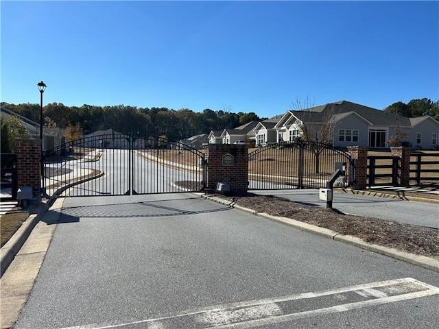 view of road featuring curbs, a gated entry, a gate, and a residential view