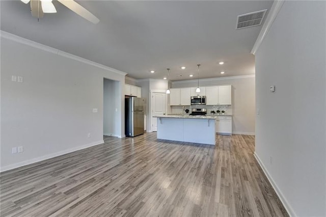 kitchen with visible vents, decorative backsplash, appliances with stainless steel finishes, open floor plan, and white cabinetry