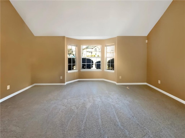 carpeted empty room with baseboards and lofted ceiling