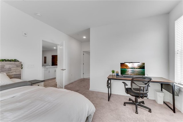 bedroom with ensuite bathroom and light colored carpet