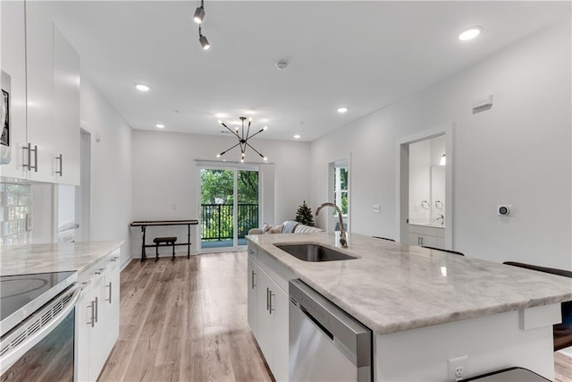 kitchen featuring white cabinets, a center island with sink, sink, light hardwood / wood-style floors, and stainless steel dishwasher