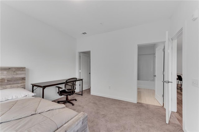 bedroom featuring connected bathroom and light colored carpet