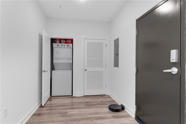 hall with stacked washer / dryer, light hardwood / wood-style flooring, and electric panel