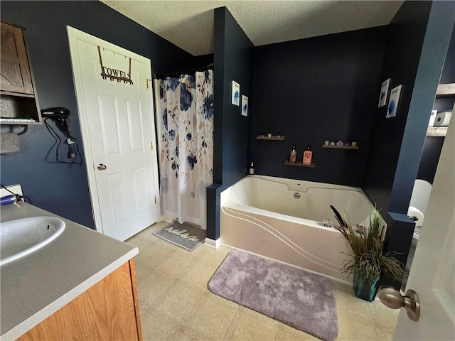 bathroom with a washtub, tile patterned floors, vanity, and a textured ceiling