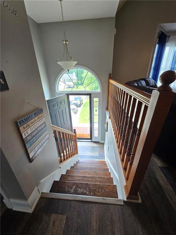 stairway with a towering ceiling and hardwood / wood-style floors