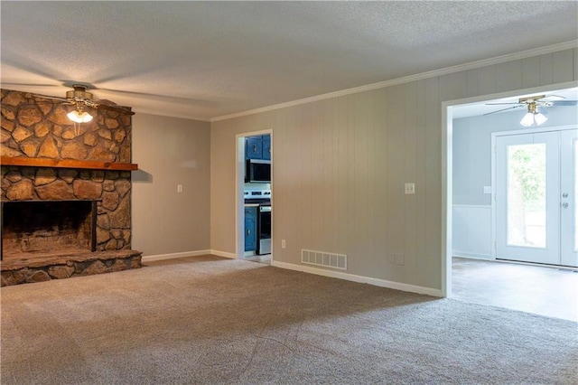 unfurnished living room with ceiling fan, a textured ceiling, carpet, crown molding, and a fireplace