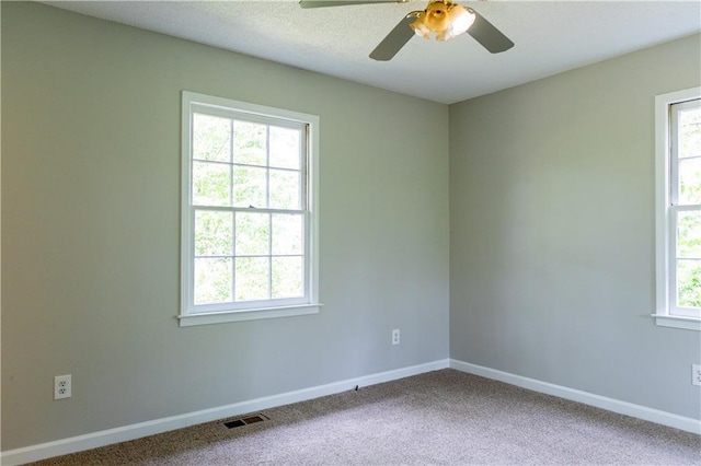 carpeted empty room with a ceiling fan and baseboards
