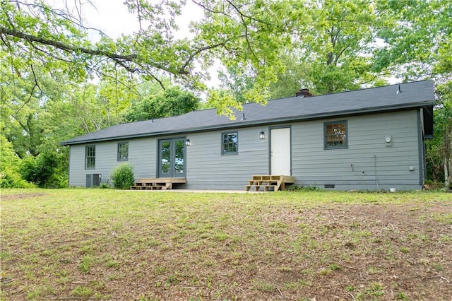 rear view of house with entry steps, crawl space, central AC unit, a lawn, and a chimney