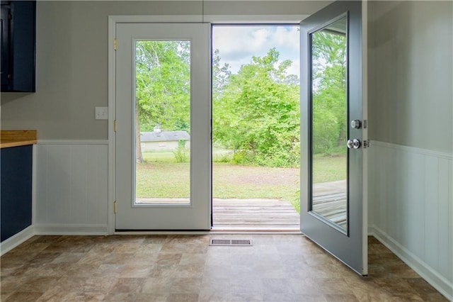 doorway to outside featuring a wainscoted wall and a decorative wall