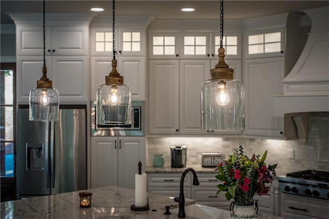 kitchen with a healthy amount of sunlight, white cabinets, backsplash, and appliances with stainless steel finishes