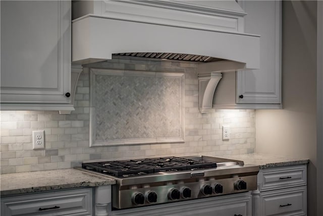 kitchen featuring light stone countertops, stainless steel gas stovetop, and tasteful backsplash