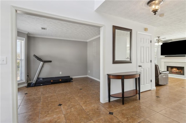 exercise area with a textured ceiling, a warm lit fireplace, and tile patterned flooring