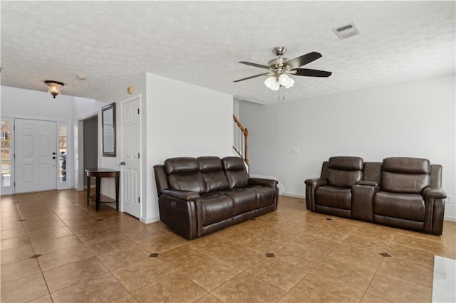 living area featuring visible vents, baseboards, ceiling fan, stairway, and a textured ceiling